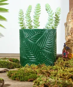 Detailansicht eines dunkelgrünen Harztopfs mit Blattrelief und Moosumgebung im Gartenstil