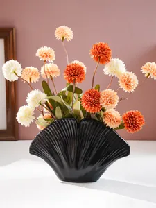 Detail van moderne zwarte harsvaas in schelpvorm met decoratieve bloemen voor in huis.
