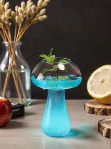 Close-up of a mushroom-shaped cocktail glass filled with blue beverage and mint.