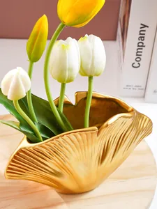 Gedetailleerd macro-zicht op een gouden schelpvormige harsvaas met elegante tulpen