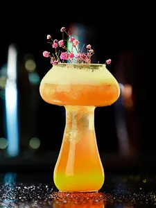Unique mushroom-shaped cocktail glass with foam and dried flower garnish in bar setting