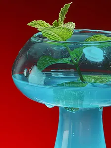 Detailed macro shot of blue cocktail in mushroom-shaped glass with mint leaves