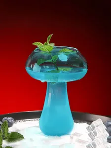 Close-up of mushroom-shaped glass filled with vibrant blue cocktail and mint