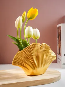 Detail van een gouden harsvaas in schelpvorm voor elegante bloemendecoratie in huis