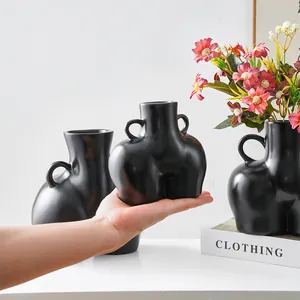 Jarrón creativo de resina negro mate con forma de glúteos y elegantes asas decorativas.