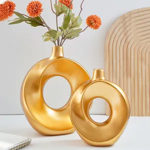Nahaufnahme moderner goldener Keramik-Donut-Vasen für minimalistische Wohndekoration