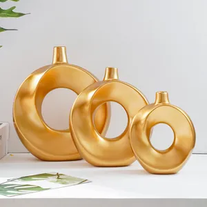 Detailansicht von drei eleganten goldenen minimalistischen Donut-Vasen aus Keramik für Deko.