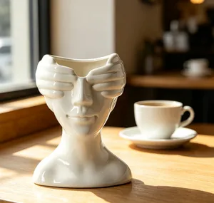 Vue détaillée d'un vase sculpture visage abstrait blanc sur une table en bois.