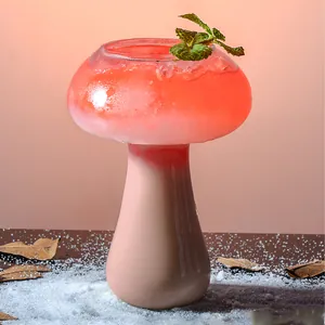 Creative mushroom-shaped glass cocktail cup featuring a layered red drink with mint leaves