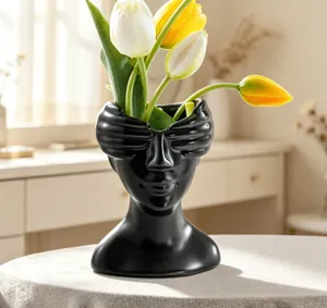 Gros plan d'un vase moderne en résine noire au design abstrait de sculpture d'un buste humain.