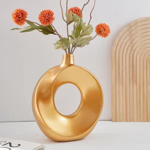 Moderne goldene ringförmige Keramikvase mit orangefarbenen Kunstblumen Deko