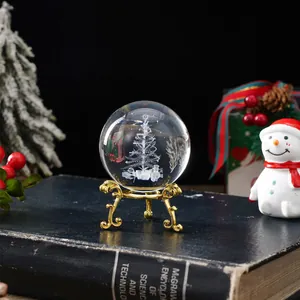 Bola de cristal detallada con grabado de árbol de Navidad sobre un soporte dorado