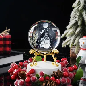 Bola de cristal navideña con escena de muñeco de nieve sobre un elegante soporte dorado