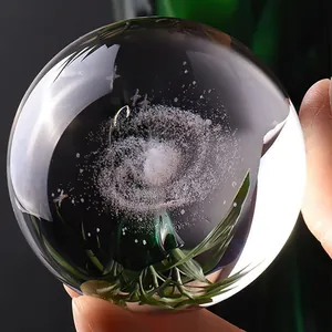 Detail view of a laser-engraved crystal ball featuring a galaxy and plant design