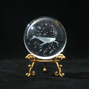Macro view of a laser engraved crystal ball with a whale motif and gold stand