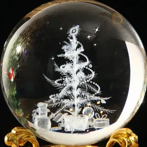 Primer plano de una bola de cristal navideña con árbol y muñeco de nieve grabados en 3D
