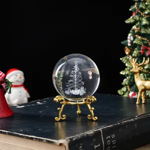 Detalle de bola de cristal con árbol de Navidad grabado con láser en soporte dorado.