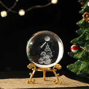 Detalle macro de bola de cristal navideña con muñecos de nieve grabados y soporte dorado