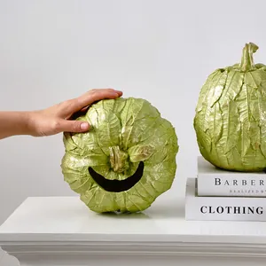 Gros plan d'un ornement de citrouille vert à texture de feuilles avec un sourire gravé