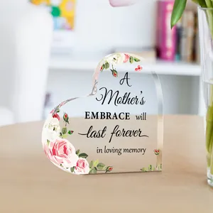 Close-up of a heart-shaped acrylic plaque with floral details and sentimental text