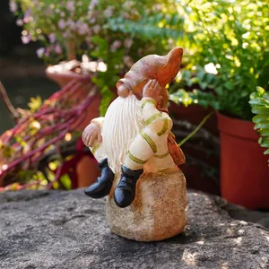 Macro view of a bearded resin garden gnome sitting on a stone in a sunny garden.