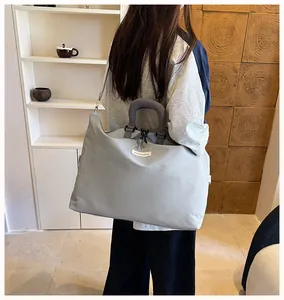 Modella che indossa una grande borsa da viaggio grigia in un moderno ambiente interno