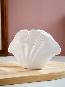 Gedetailleerd zicht op een witte schelpvormige harsvaas met fijne geribbelde textuur.