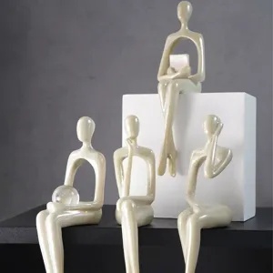 Macro di figurine minimaliste perlescenti in varie pose sedute per l'arredamento casa.
