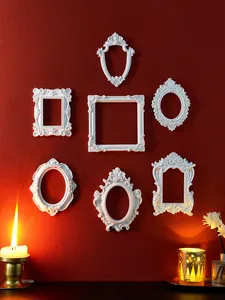 Collection of white vintage European ornate relief frames displayed on a dark red wall
