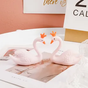 Gros plan de deux figurines de cygne rose avec des couronnes orange sur des accessoires