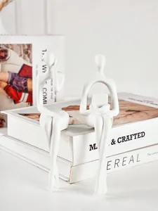 Deux figurines abstraites blanches minimalistes sur des livres décoratifs pour la maison