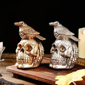 Close-up of gold and silver resin skull sculptures with perched crows for Halloween decor