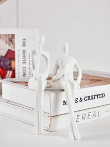 Vue détaillée de deux figurines humaines abstraites blanches minimalistes posées sur des livres