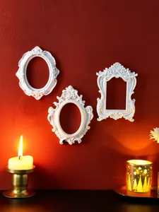 Set of 3 white vintage baroque relief frames for wall decor in a warm candlelit setting