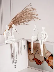 Détail de quatre sculptures humaines abstraites blanches assises sur un support minimaliste