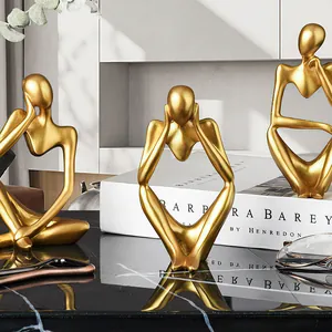 Vista detallada de tres estatuas doradas de pensador abstracto sobre un escritorio de mármol