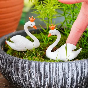 Gros plan de deux figurines de cygnes blancs avec couronnes oranges sur mousse