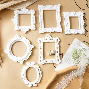Detailed view of white ornate baroque style resin frames with vintage flower motifs.