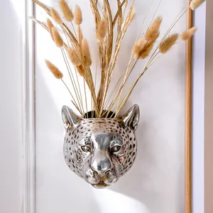 Detailed view of silver leopard head wall-mounted vase with dried decorative grass