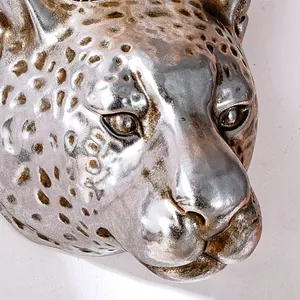Close-up macro view of a silver leopard head wall decor showing metallic texture.