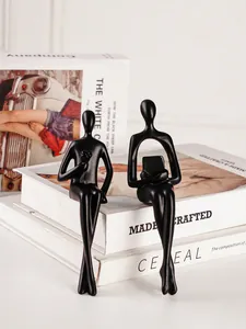 Paire de statues de penseurs abstraits noirs assis sur des livres pour décoration.