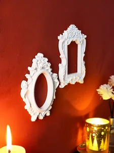 Detail view of white baroque relief frames on a red textured wall with warm light.