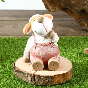 Detailopname van een schattig schaapje van hars met roze tuinbroek voor in de tuin.