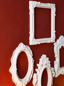 Ornate white Baroque style relief frames mounted on a textured red wall
