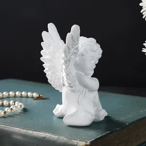 Detail view of a white resin cherub angel figurine resting on an antique green book