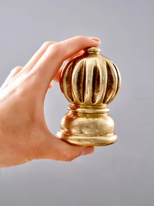 Detalle de un remate de asta de bandera dorado con forma de calabaza sostenido en mano
