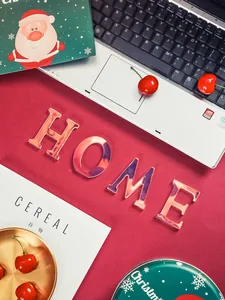 Détail des lettres 'HOME' en acrylique iridescent sur un fond rouge festif