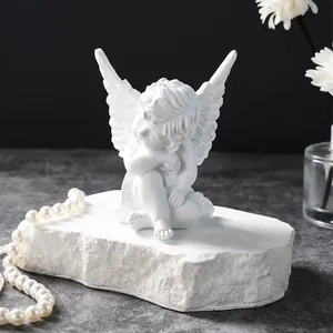 Close-up view of a detailed white resin angel figurine on a textured stone base