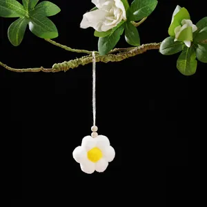 Macro view of a handmade white and yellow pom-pom flower charm with natural wood beads