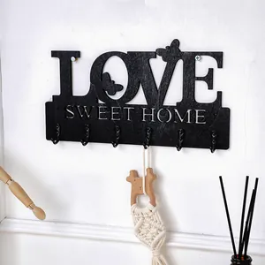 Detailansicht einer schwarzen hölzernen LOVE SWEET HOME Wandgarderobe mit sechs Metallhaken